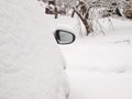 Car mirror of a snow-covered car against the backdrop of a snow-covered garden Royalty Free Stock Photo
