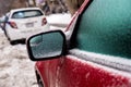 Car mirror and windows are covered with ice after freezing rain.