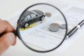 Car model under magnifying glass in woman hand suggesting car search