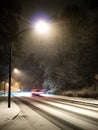 Car with motion blur driving on a snowy street with street lights at night Royalty Free Stock Photo