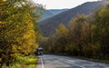 The car moves along a winding asphalt road among the mountains.