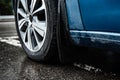 Car mudgaurd, mudflap on front wheel of blue car parking on wet asphalt. Royalty Free Stock Photo