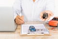 Close-up shot of hand of agent handing car keys to the customer after signing a car rental and purchase contract form Royalty Free Stock Photo