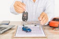 Close-up shot of hand of agent handing car keys to the customer after signing a car rental and purchase contract form Royalty Free Stock Photo