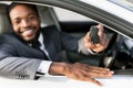 Car owner. Happy man showing key, sitting in auto