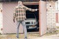 A car owner looking on his white classic convertible BMW E30 car in the half opened garage.