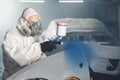 Car paint worker spraying blue paint to car body element using spray gun in vehicle workshop chamber. Complex Royalty Free Stock Photo