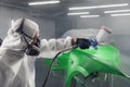 Car paint worker spraying green paint to car body element using spray gun in vehicle workshop chamber. Complex Royalty Free Stock Photo