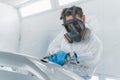 Car painter applies a layer of varnish to the surface of a car bumper.