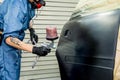 car painter paints the fender of a car