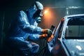 Car painter in protective clothes and mask painting a car, mechanic using a paint spray gun in a painting chamber. Bodywork, paint Royalty Free Stock Photo