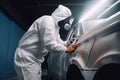 Car painter in protective clothes paints automobile with paint in chamber workshop. Generative AI Royalty Free Stock Photo