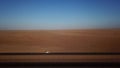 Car parked on asphalt road in aerial desert. Sandy landscape, nobody in Namibia.