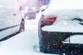 Car parked on city street covered with thick snow layer during snowstorm blizzard at winter. Vehicle tail at cold winter morning