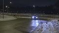 Car parked on the empty snowy road at night with its headlights on. Action. Lonely car with neon headlights standing on