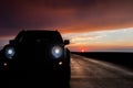 A car parked in front of the sunset