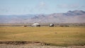 A car is parked at a nomadic yurt in the lowlands of central Mongolia, with mountains towering in the background. Royalty Free Stock Photo