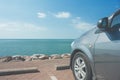 Car parked on parking lot at seashore near the beach with seascape and blue sky in the background. Royalty Free Stock Photo