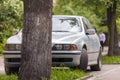 Car parked in pedestrian zone under trees along street with walking people on summer day Royalty Free Stock Photo