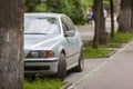 Car parked in pedestrian zone under trees along street with walking people on summer day Royalty Free Stock Photo