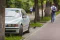 Car parked in pedestrian zone under trees along street with walking people on summer day Royalty Free Stock Photo