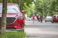 Car parked in pedestrian zone under trees on city street with walking people on summer day Royalty Free Stock Photo