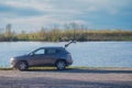 Car is parked in a scenic location by a lake, with the trunk open