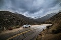 Car parked on scenic mountain wet road curve at rainy cloudy day. Road trip concept Royalty Free Stock Photo