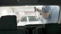Car passing through the car wash, a person washes the car with a non-contact sink, a view from inside the car