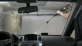 Car passing through the car wash, a person washes the car with a non-contact sink, a view from inside the car
