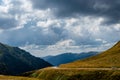 Car passing on mountain road with mountains in the background and dark clouds above Royalty Free Stock Photo