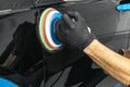 Car polish wax worker hands applying protective tape before polishing. Buffing and polishing car. Car detailing. Man holds a polis