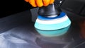Car polish wax worker hands applying protective tape before polishing. Buffing and polishing car. Car detailing. Man holds a polis Royalty Free Stock Photo