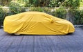 A car with a protect covered. Yellow sheet on the pavement