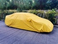 A car with a protect covered. Yellow sheet on the pavement