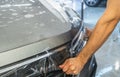 Car protection film or PPF process of wrapping and installing on car hood by detailer worker hands, close up