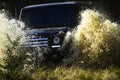 Car racing in autumn forest. SUV or offroad car on path covered with grass crossing puddle with water splash. Extreme Royalty Free Stock Photo