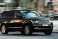car Range Rover L405 side view. Sport SUV black color driving against blurred city background. Full size luxury crossover in Royalty Free Stock Photo