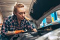 Car reapir. Young red-headed girl, auto mechanic working at auto service station using different work tools. Gender Royalty Free Stock Photo