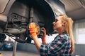 Car reapir. Young red-headed girl, auto mechanic working at auto service station using different work tools. Gender Royalty Free Stock Photo