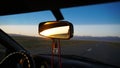 Car rear view mirror. Displays orange dawn. Visible road, hills and steppe. Royalty Free Stock Photo