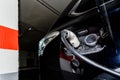 A car recharges its electric batteries inside a private garage with its own charging station, detail of the connected plug