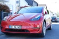 car in red color on street, charging with electricity through cable, electric vehicle in European city, energy cylindrical