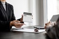 A car rental company employee holds a white calculator to show the tenant the rental price.