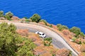 Car rental during the travel concept. White car driving by the serpentine road over the sea.