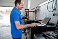 Car repair and maintenance theme. Electric mechanic in uniform working in auto service, making car diagnostics using obd device Royalty Free Stock Photo