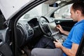 Car repair and maintenance theme. Electric mechanic in uniform working in auto service, making car diagnostics using obd device Royalty Free Stock Photo