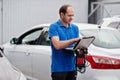 Car repair and maintenance theme. Electric mechanic in uniform working in auto service, making car diagnostics using obd device Royalty Free Stock Photo