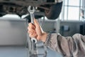 Car repair, maintenance and vehicle inspection concept. Man holding wrench in front of a car Royalty Free Stock Photo