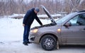 Car repair on the road in winter. a young man is trying to fix a car breakdown under the soot on the road. woodsroadside Royalty Free Stock Photo